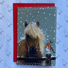 A square greeting card featuring a close-up photo of a horse in the snow with a small bird perched on its nose, placed on top of a red envelope against a patterned blue gift wrap background.