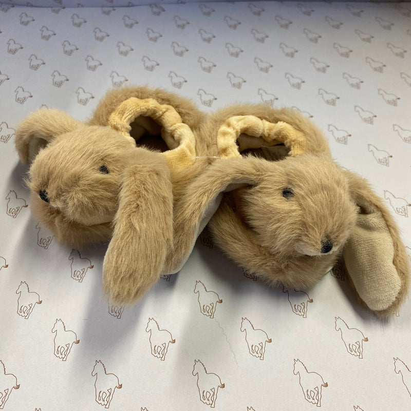 Pair of plush bunny slippers on a patterned surface