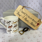 A white ceramic mug printed with various horse illustrations, displayed alongside a wooden hanging sign that reads 'I Used To Have Money Now I Have Horses' and a small gold keyring, set against a patterned background.