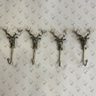Four silver metal reindeer antler coat hooks arranged in a row on a white background with a repeating brown dog pattern.