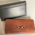 Two purses in leather with brass snaffle detail.  One in tan leather, one in black.