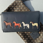 A large navy leather purse with four coloured horses stitched onto the front. The purse comes in a mala leather pouch.
